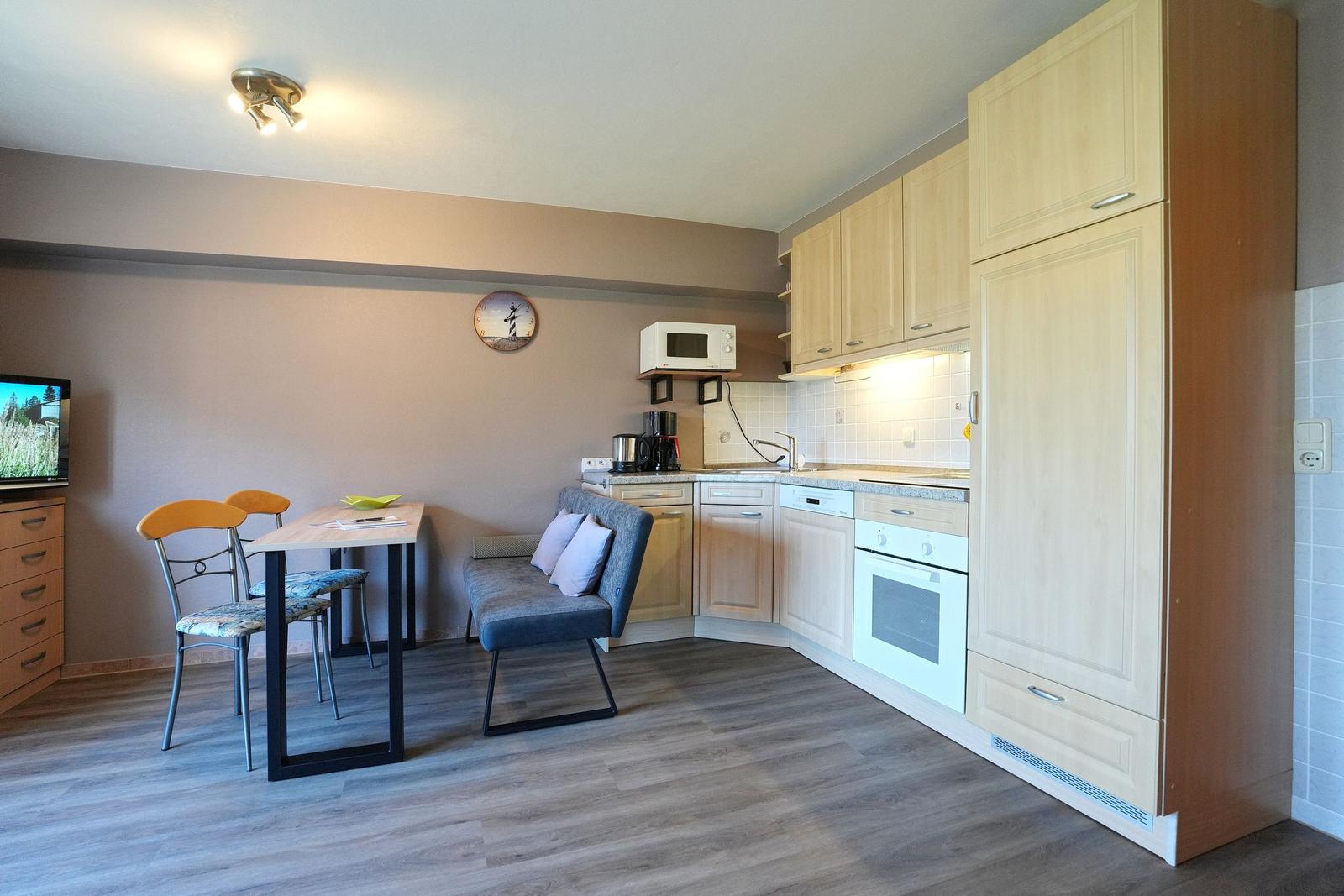 Küche mit Essbereich und Fernseher. Holzmöbel, Mikrowelle und Backofen.