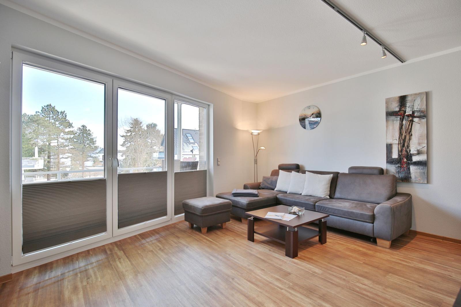 Wohnzimmer mit Sofa, Couchtisch und großen Fenstern zur Terrasse.