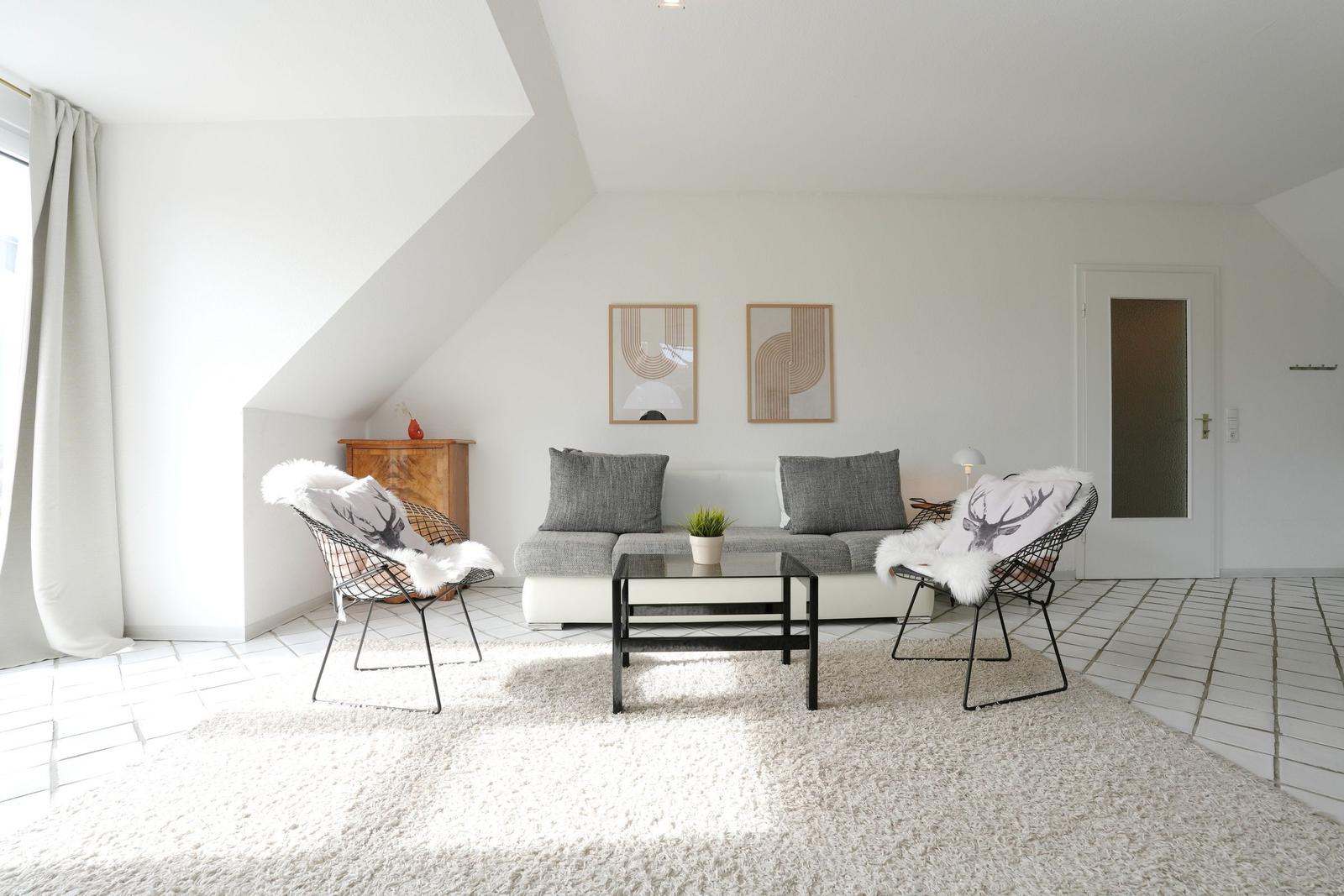 Wohnzimmer mit Sofa, zwei Sesseln und Kaffeetisch auf Teppich