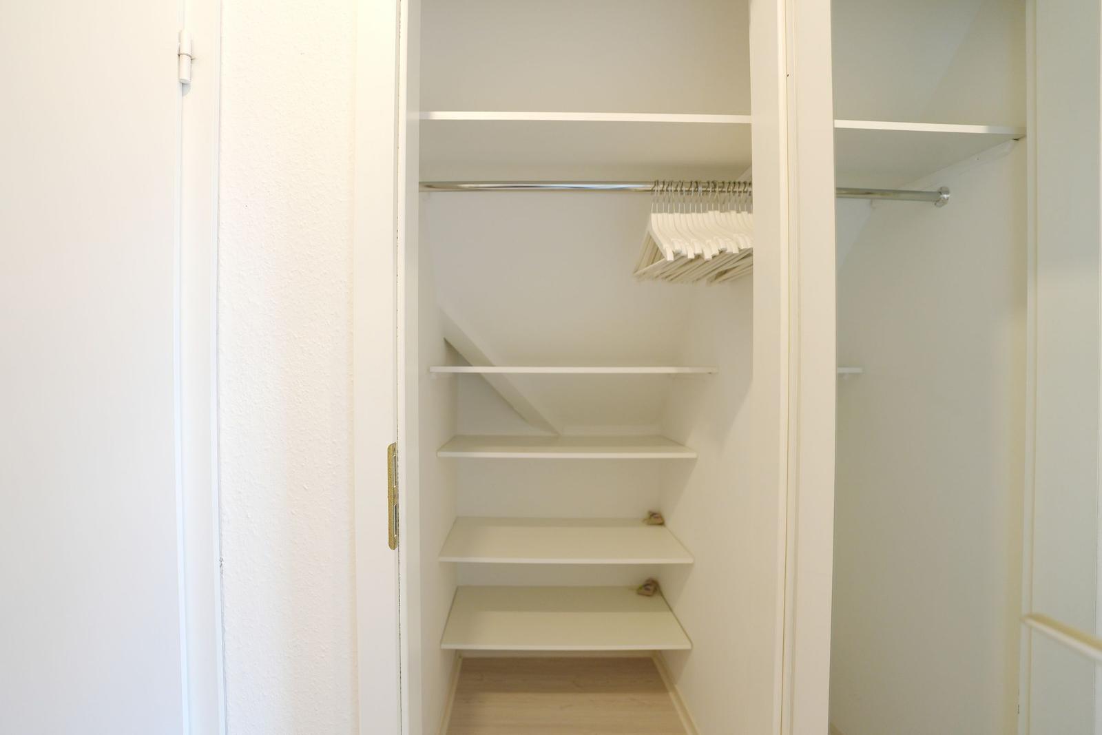 Ein kleiner Schrank mit mehreren Regalen und einem Kleiderbügel