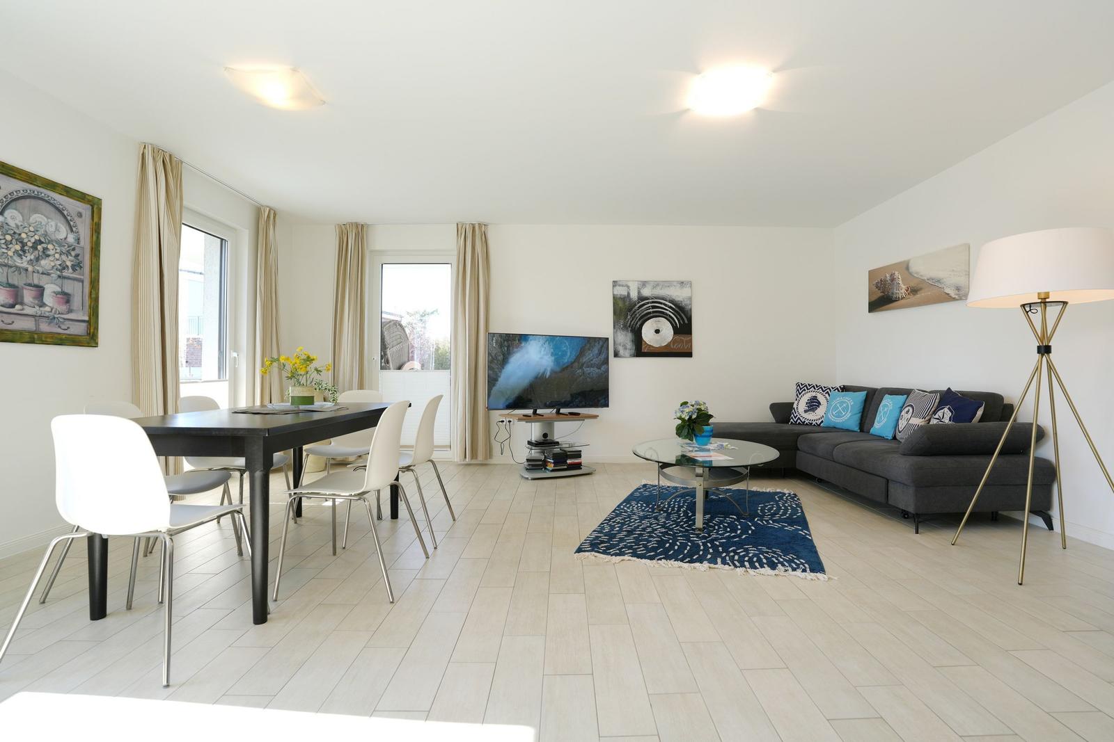 Wohn- und Essbereich mit Sofa, Esstisch und Fernseher.