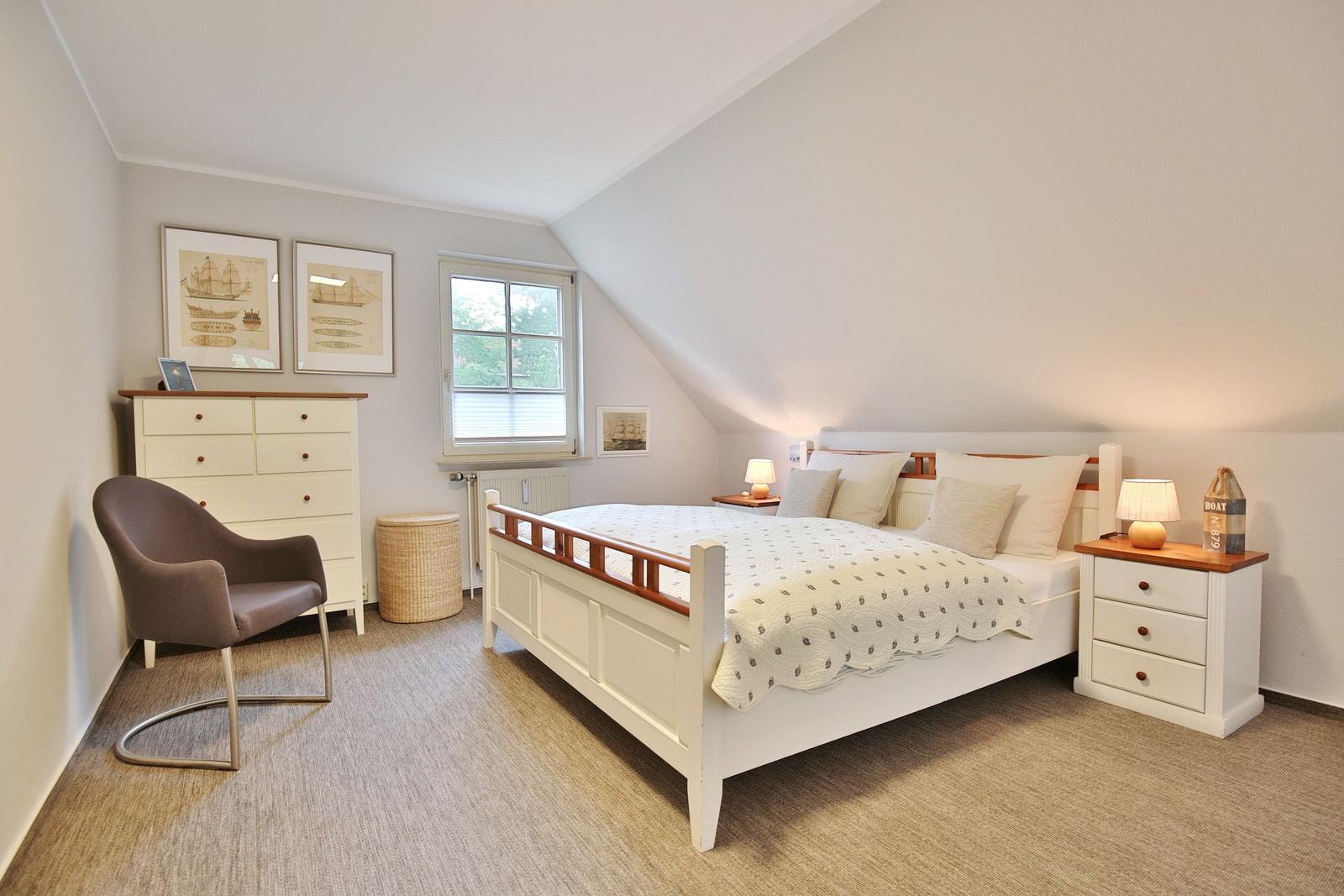 Bedroom with bed, nightstands, and dresser under sloped ceiling