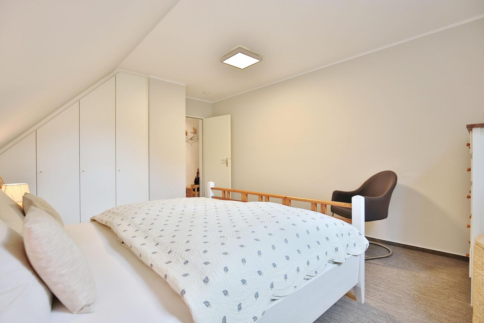 Bedroom with bed, wardrobe, and armchair.