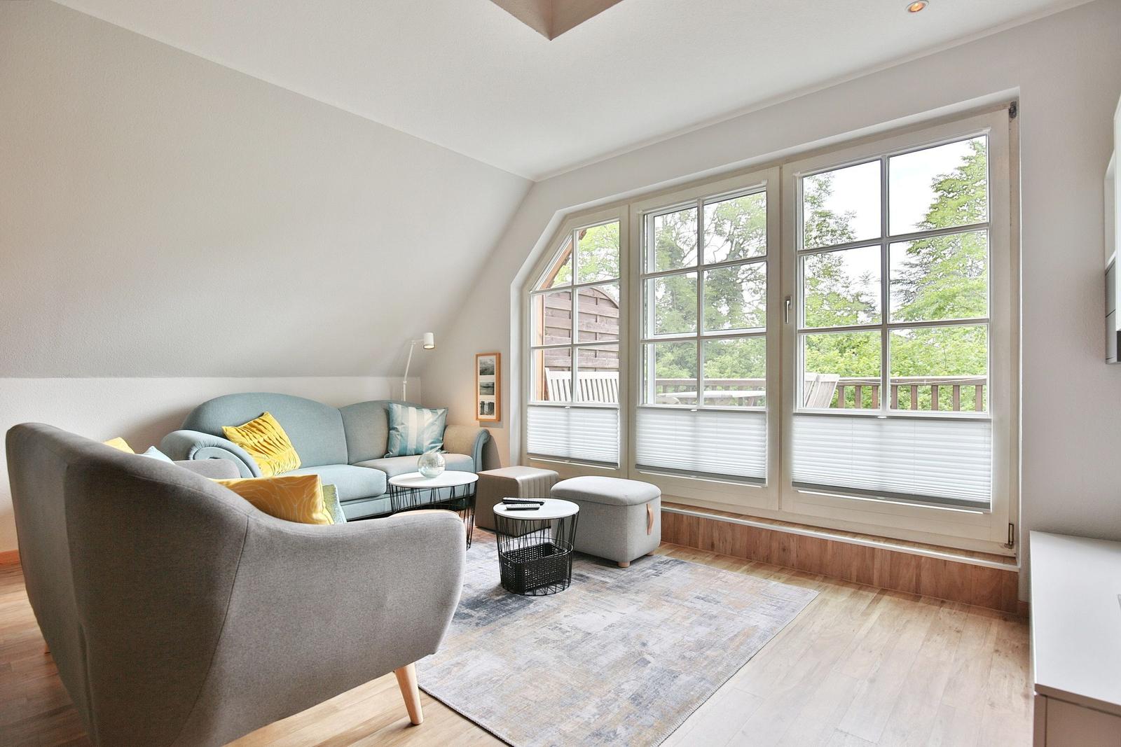 Living room with sofa, armchair, and large windows to the balcony.