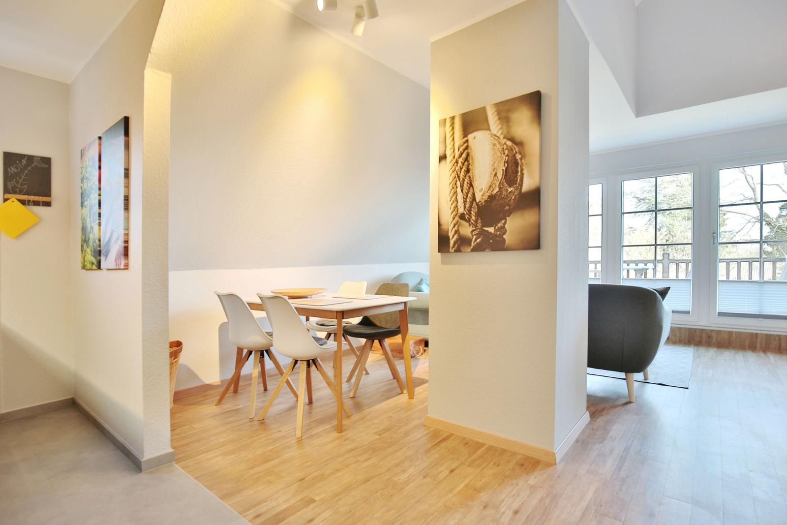 Dining area with table and chairs, wall art, and view of living area with sofa.