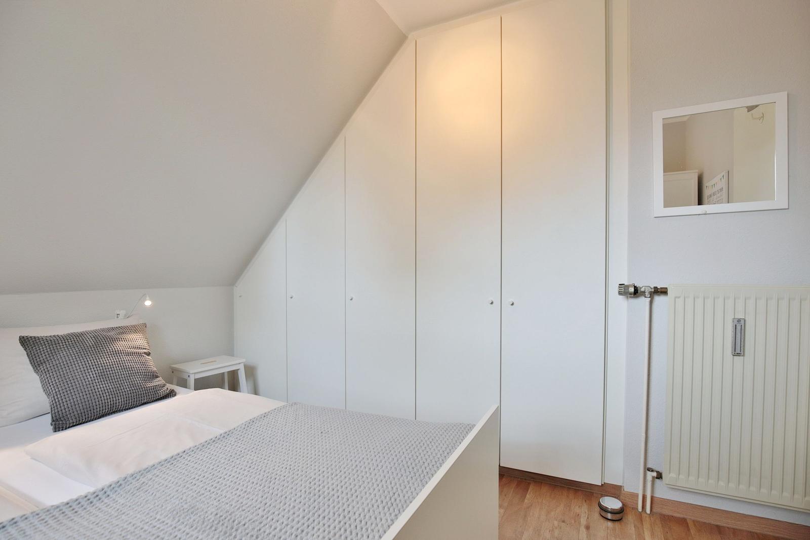 Bedroom with bed, wardrobe, and mirror on the wall.