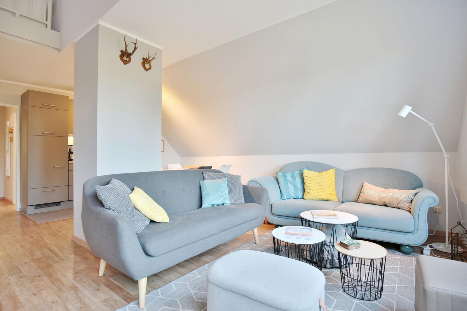 Two gray sofas with cushions, round tables, and floor lamp in living area.