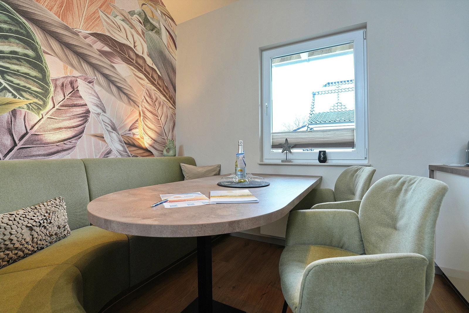 Dining area with table, chairs, and wall art. Window view of roof.