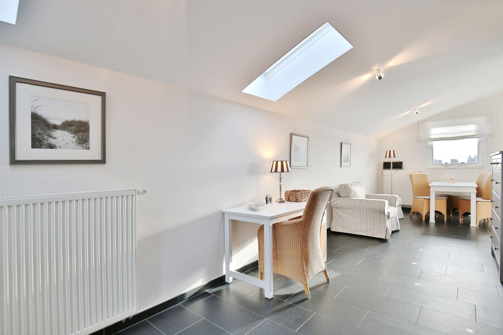 Wohn- und Essbereich mit Tisch, Stühlen und Fenster. Deckenlicht und Wandbilder sichtbar.
