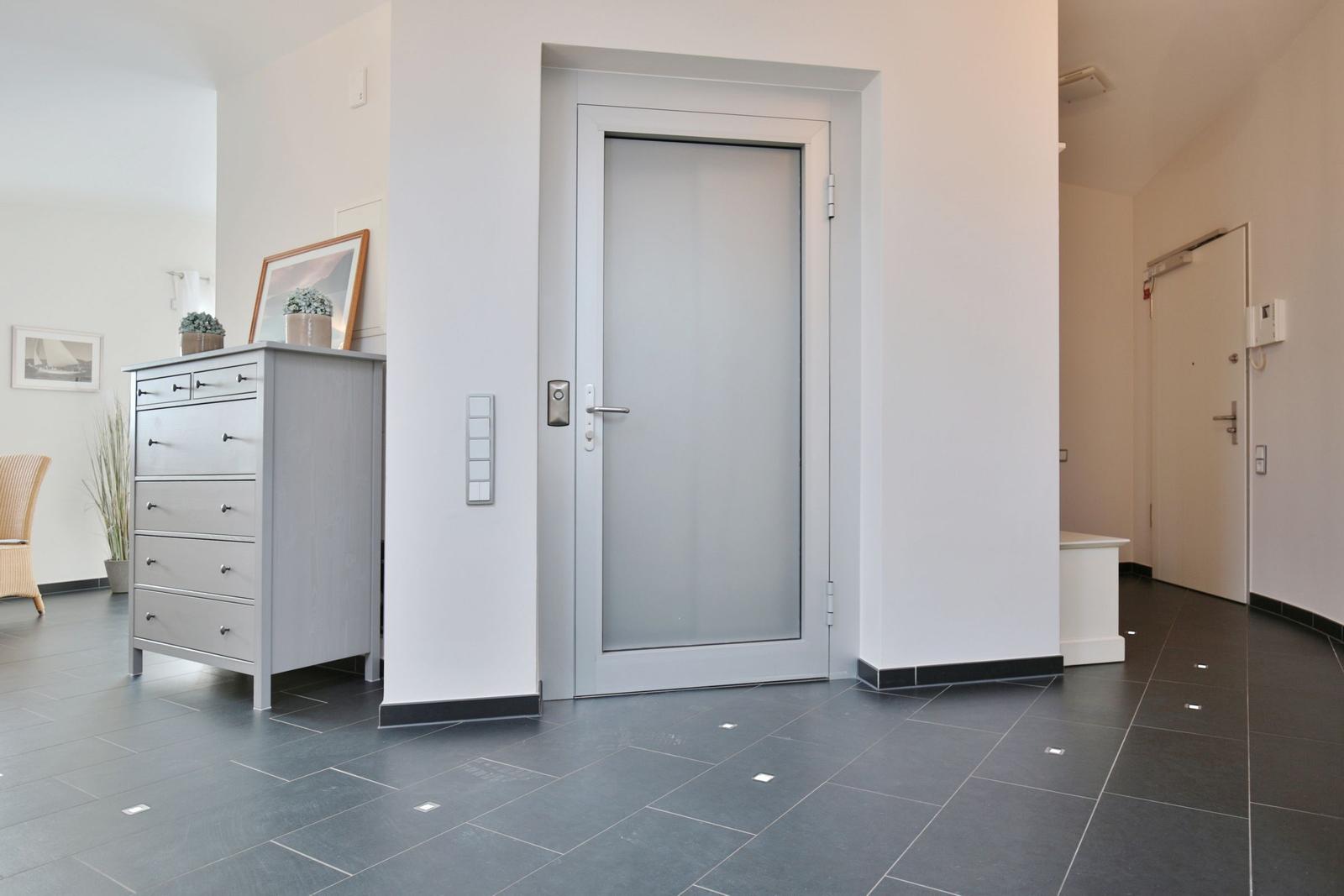 Eingangsbereich mit Tür, Schrank und Bodenfliesen.