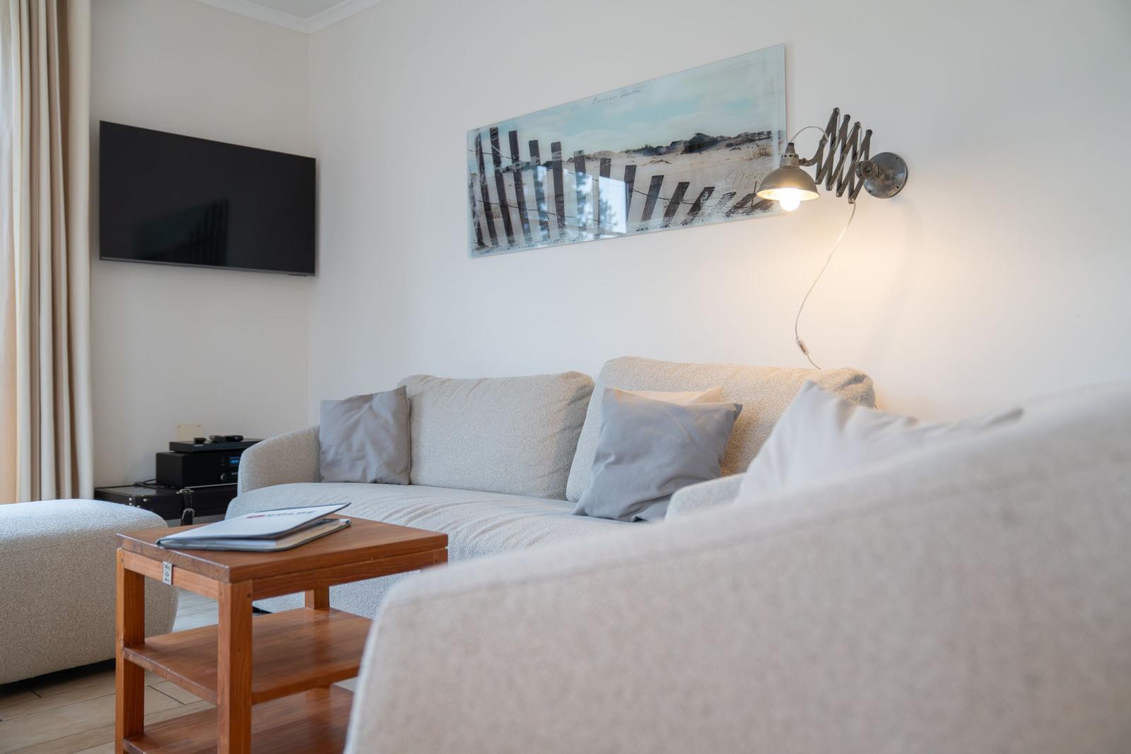 Wohnzimmer mit Sofa, Couchtisch und Wandbild. Fernseher an der Wand.