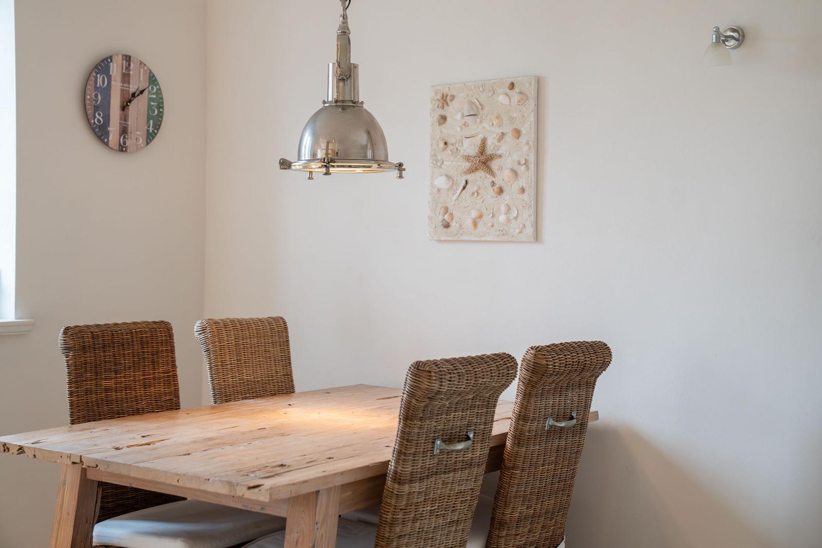 Esszimmer mit Holztisch, vier Stühlen und Wanddekoration.