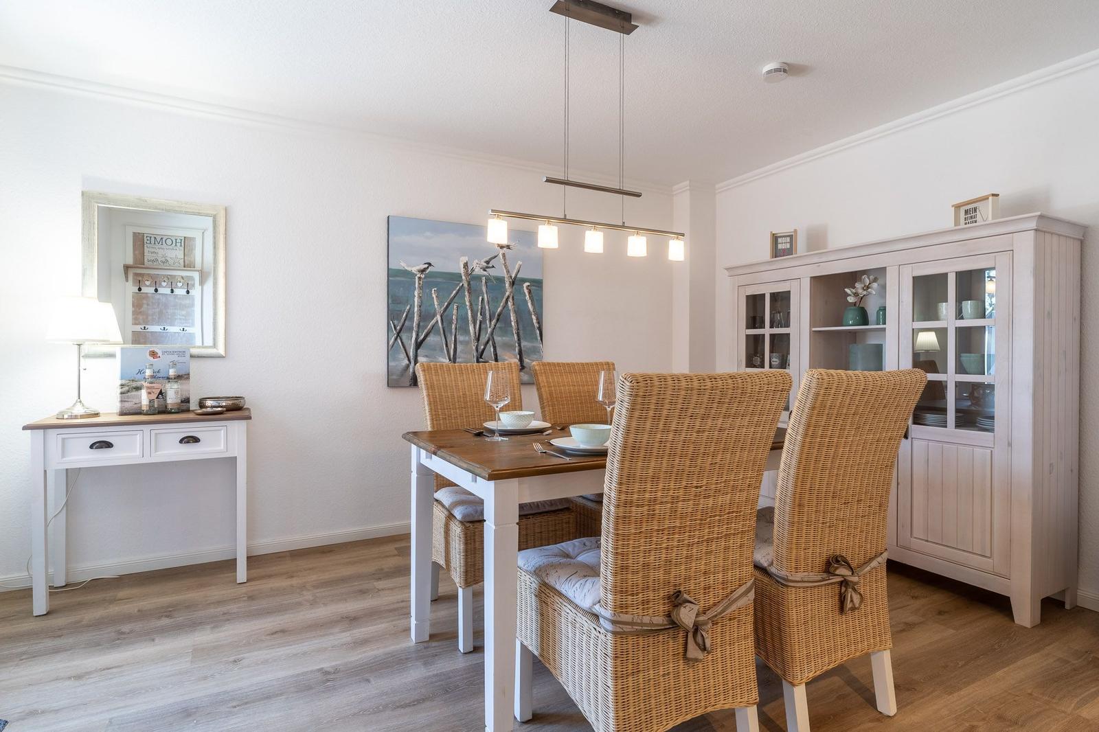 Esszimmer mit Esstisch, Stühlen und Sideboard. Wandbild und Deckenleuchte sichtbar.