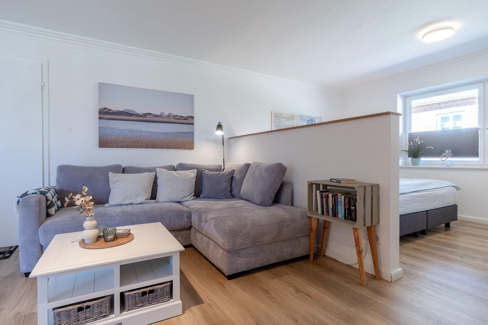 Wohnbereich mit Sofa, Couchtisch und Blick auf Schlafzimmer.