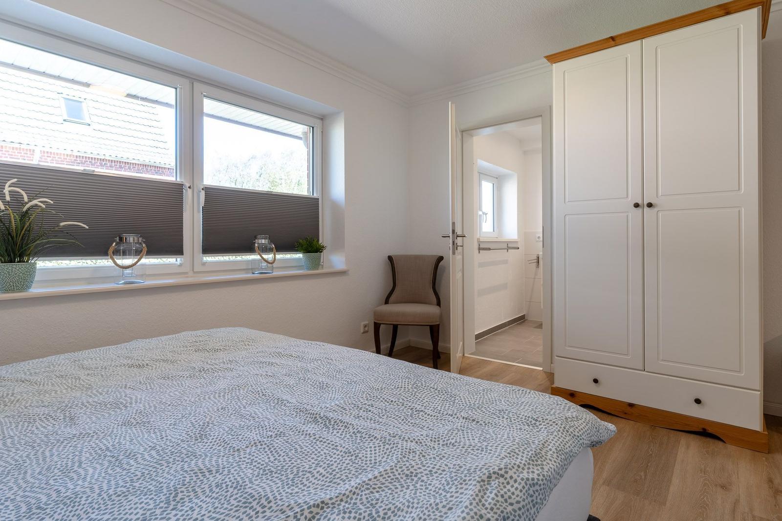 Schlafzimmer mit Bett, Kleiderschrank und Fenster mit Blick auf Dach.