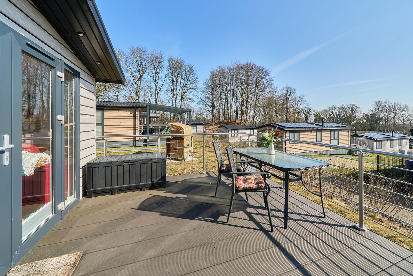 Terrasse mit Tisch, Stühlen und Blick auf Ferienhäuser.