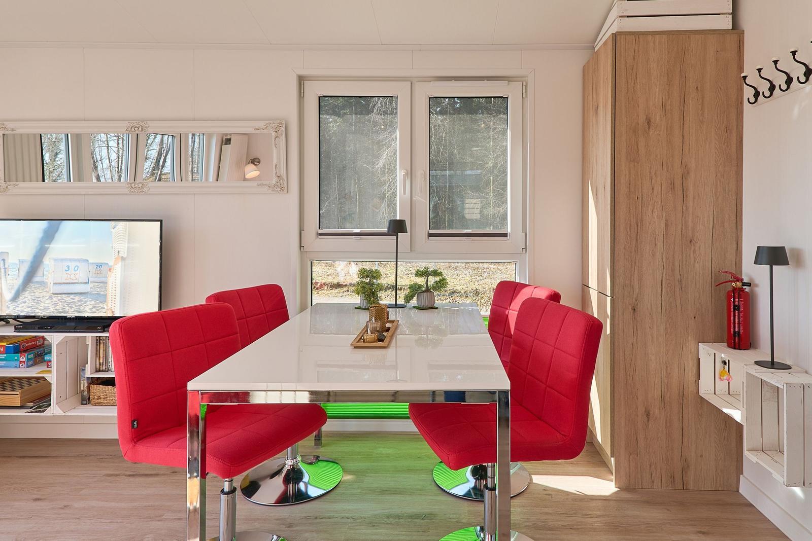 Essbereich mit roten Stühlen, Glasplatte und Fensterblick.