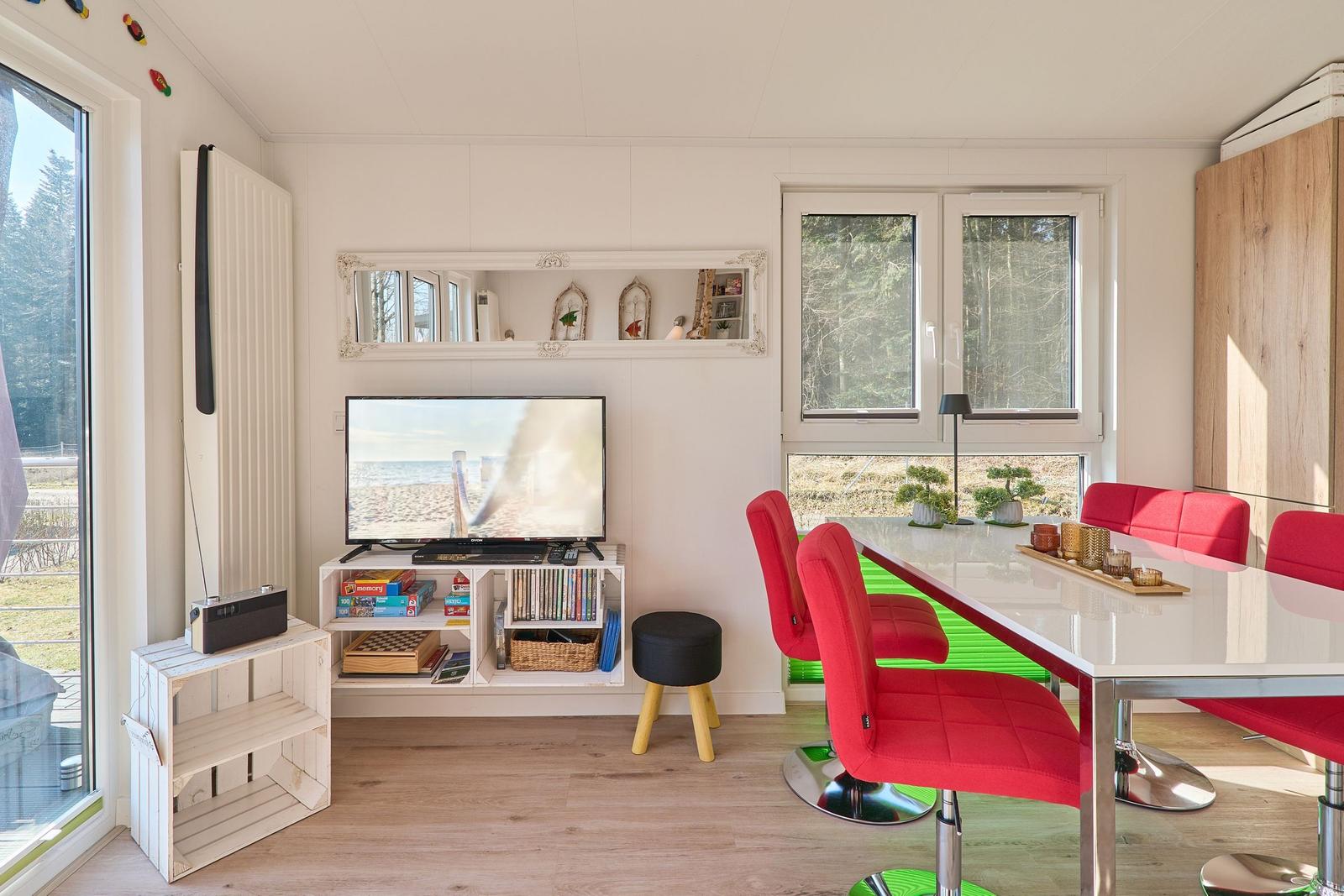 Ein Essbereich mit roten Stühlen und einem Fernseher an der Wand.