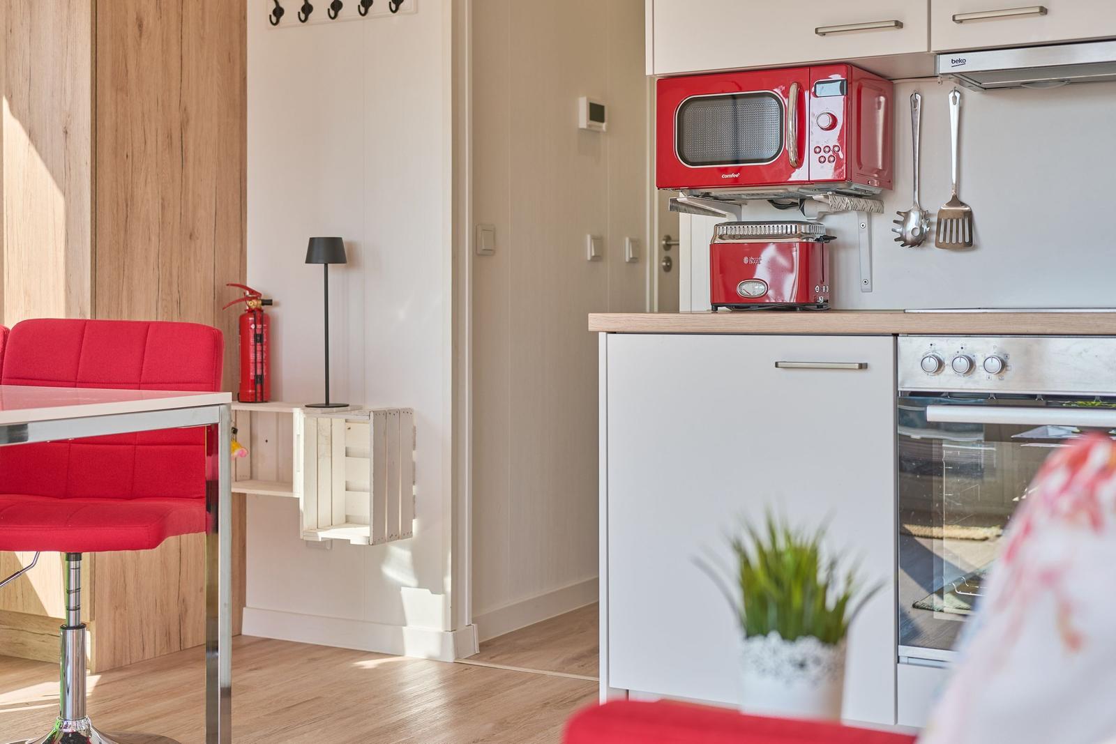 Küche mit rotem Mikrowellenherd und Toaster, weißer Arbeitsplatte und roter Sitzbank.