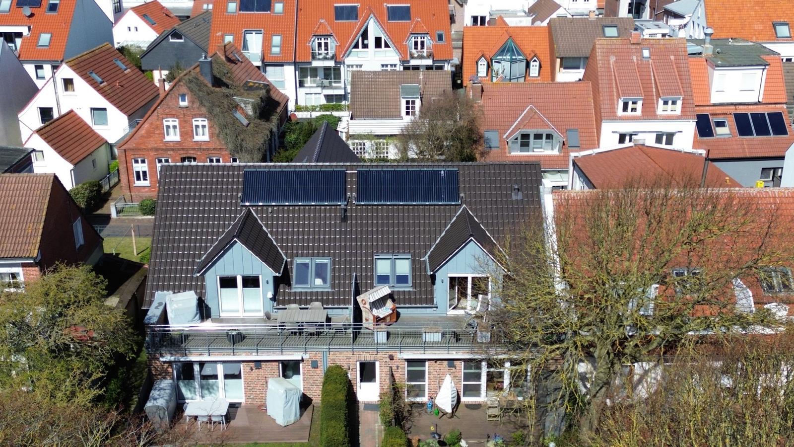 Modernes Haus mit Solaranlage, Terrasse und Gartenbereich in ruhiger Wohngegend.