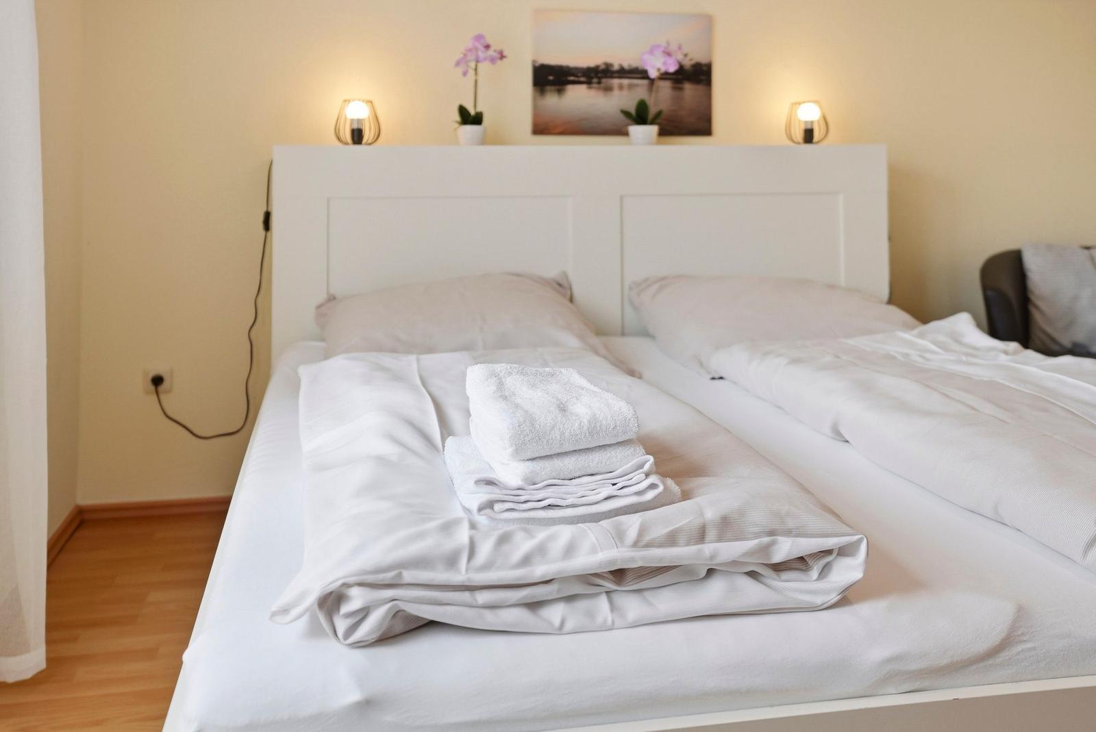 Ein Bett mit weißer Bettwäsche, Handtüchern und einer Wanddekoration.