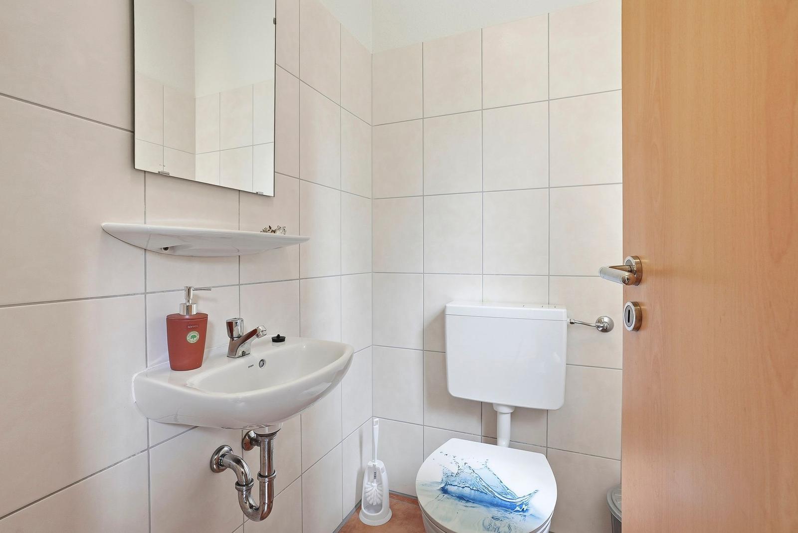 Badezimmer mit Waschbecken, Spiegel und Toilette mit Wassermotiv.