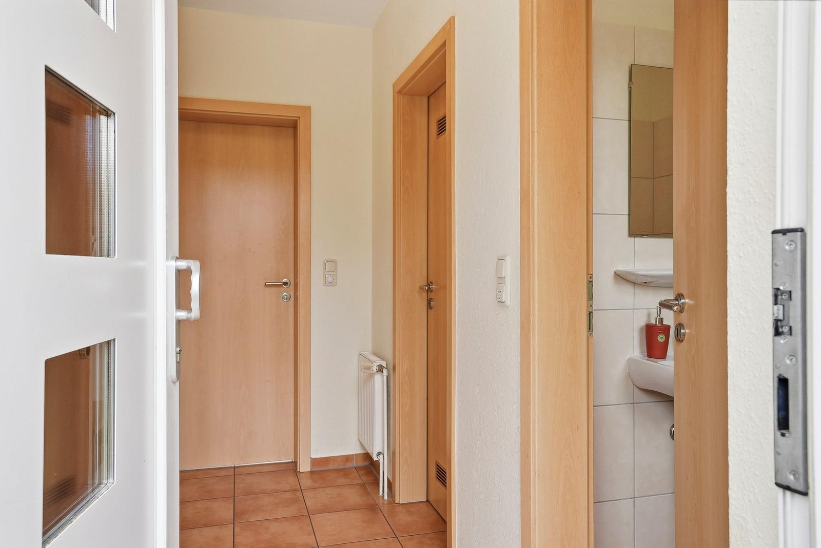 Hausgang mit Tür, Heizkörper und Blick in die Toilette.