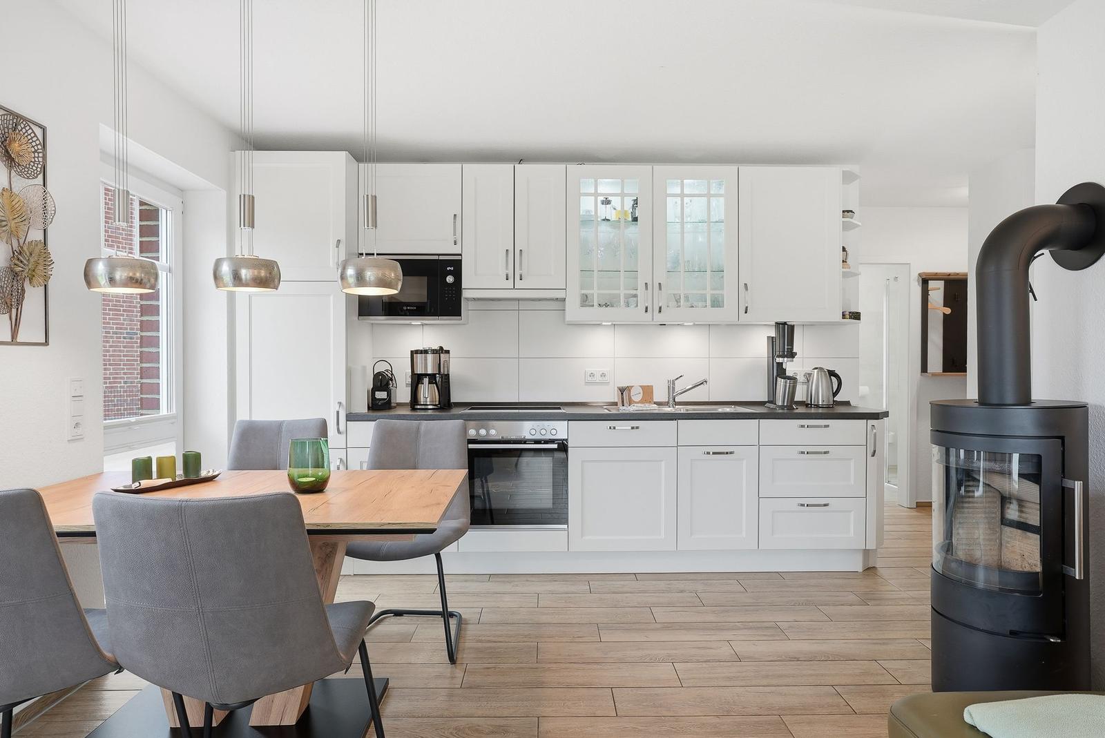 Moderne Küche mit Essbereich und Holzboden. Schwarze Arbeitsplatte und Kaminofen.