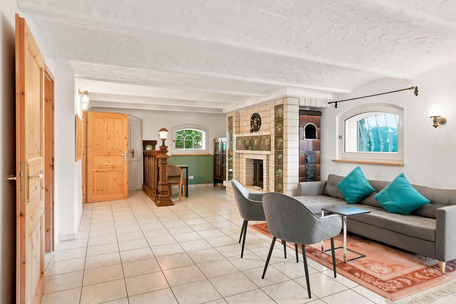 Wohnzimmer mit Sofa, Stühlen, Kamin und Holztüren.