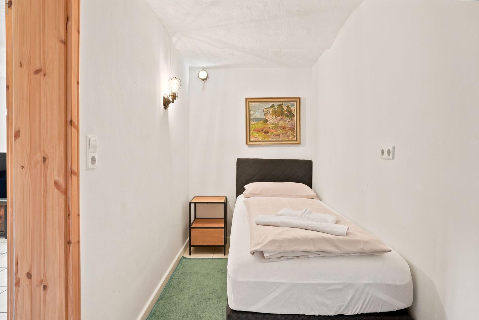 Ein Schlafzimmer mit einem Bett, einem Nachttisch und einer Wandlampe.