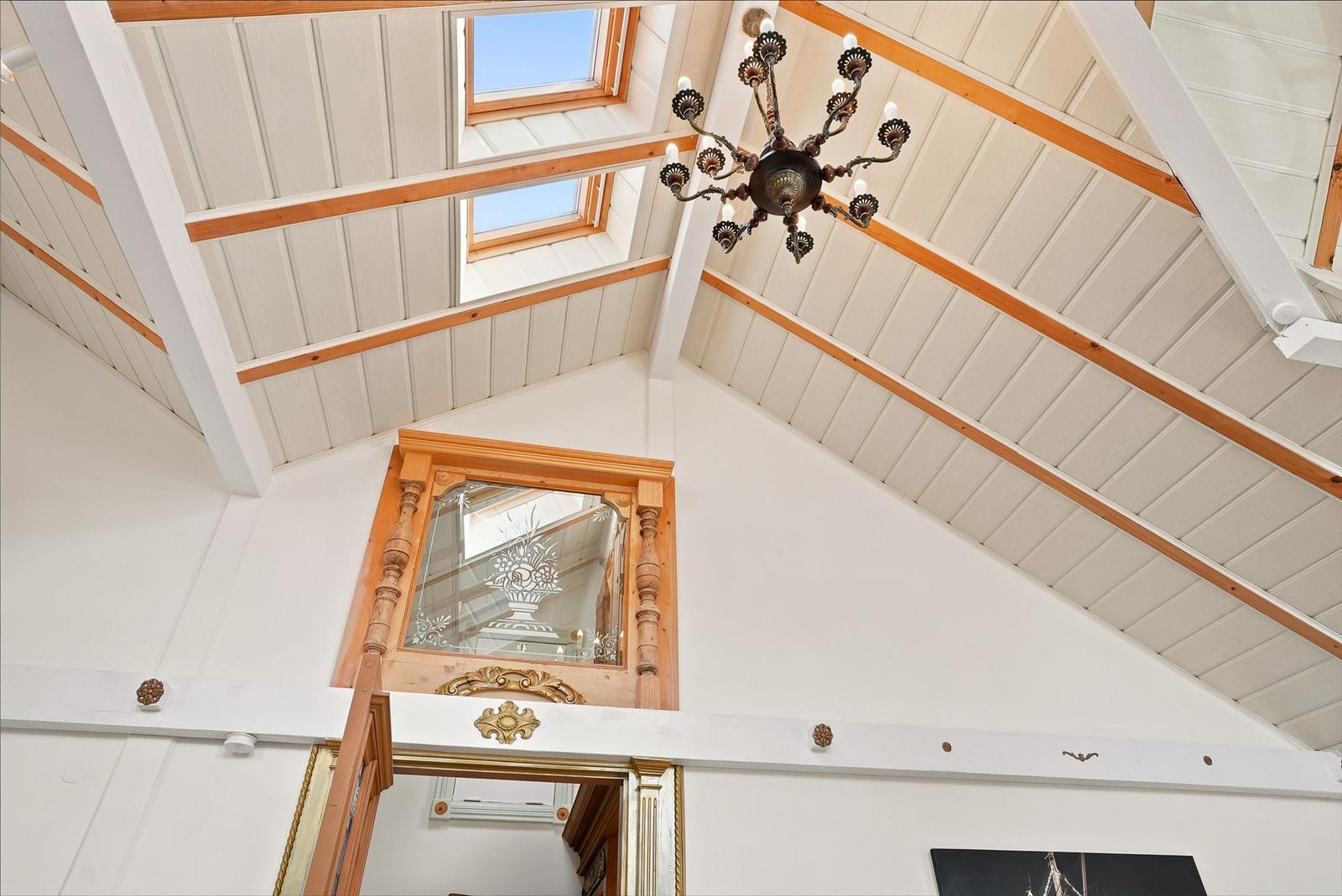 Hochwertige Decke mit Holzbalken, Dachfenstern und Kronleuchter. Spiegel mit Schnitzerei.