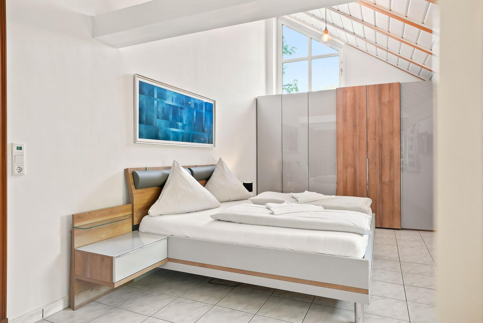 Schlafzimmer mit Doppelbett, Kleiderschrank und Fenster