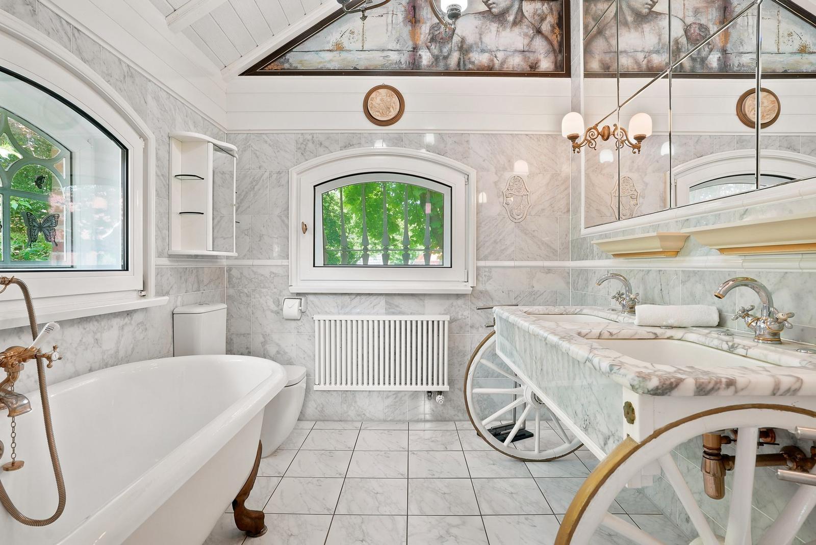 Badezimmer mit Marmor, Badewanne und Waschtisch auf Karrenbasis.