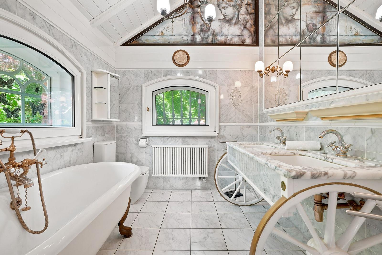 Badezimmer mit marner Wandverkleidung, Badewanne und Waschbecken auf Karrenbasis.