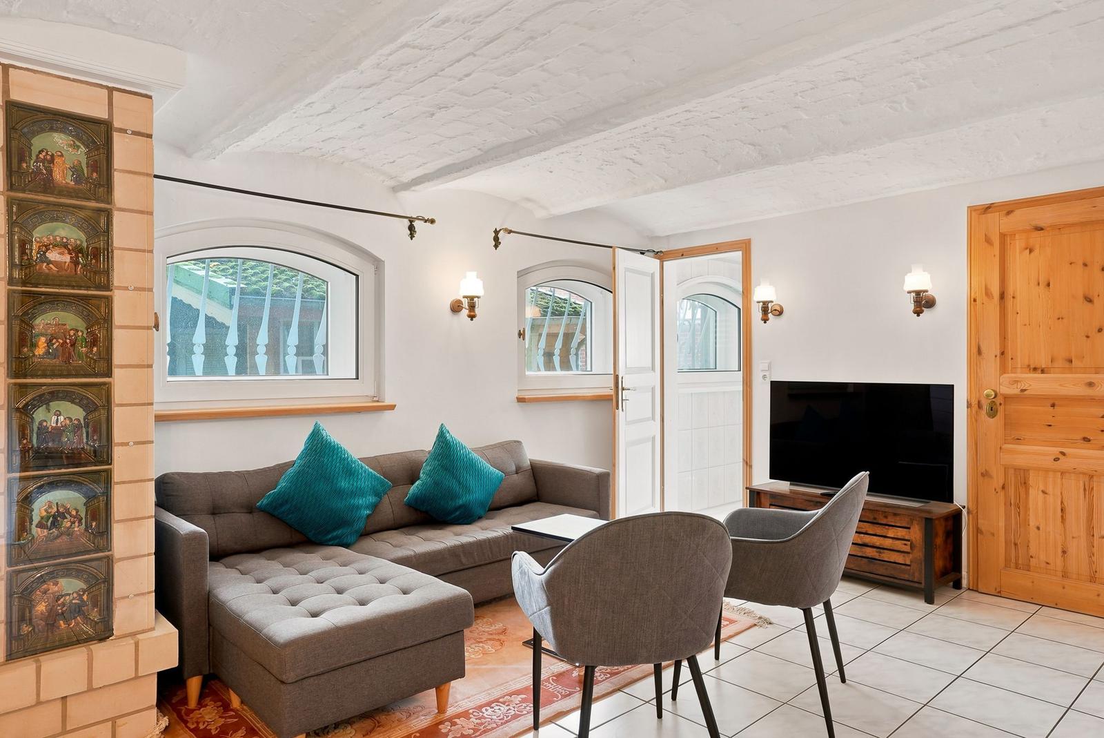 Wohnzimmer mit Sofa, zwei Stühlen, Fernseher und dekorativen Wandfliesen.