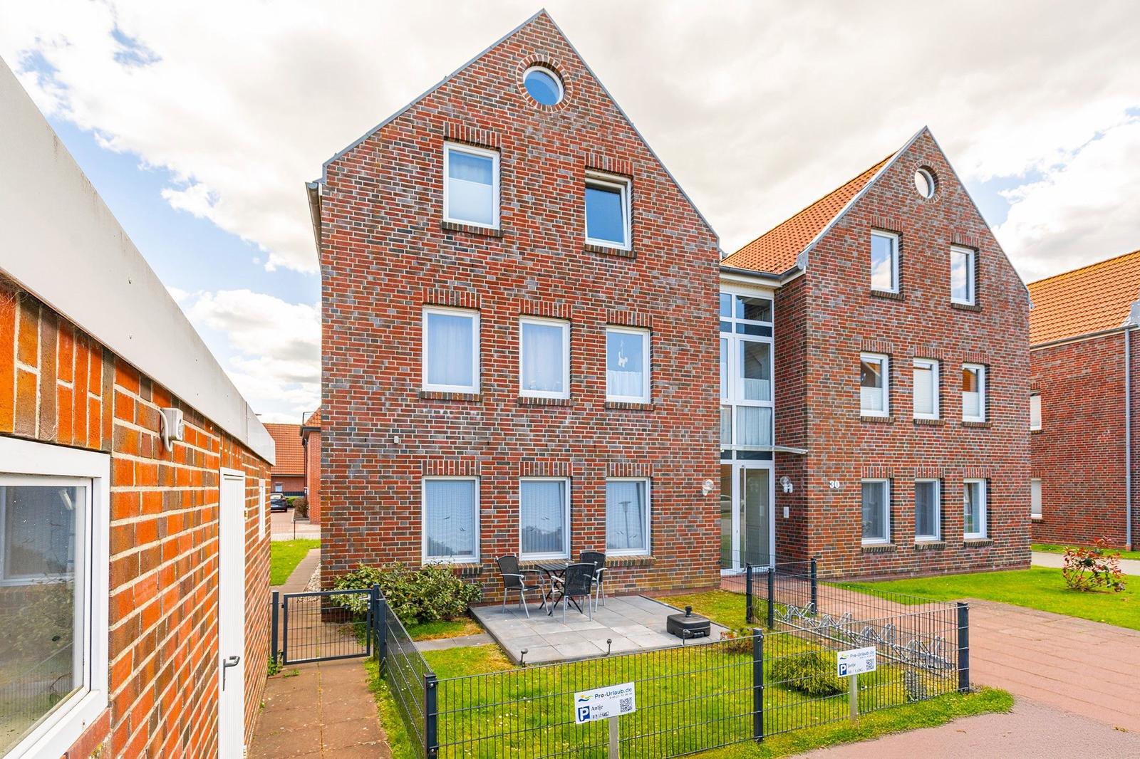 Zwei Stockwerke hohes Backsteingebäude mit Terrasse und Gartenbereich.
