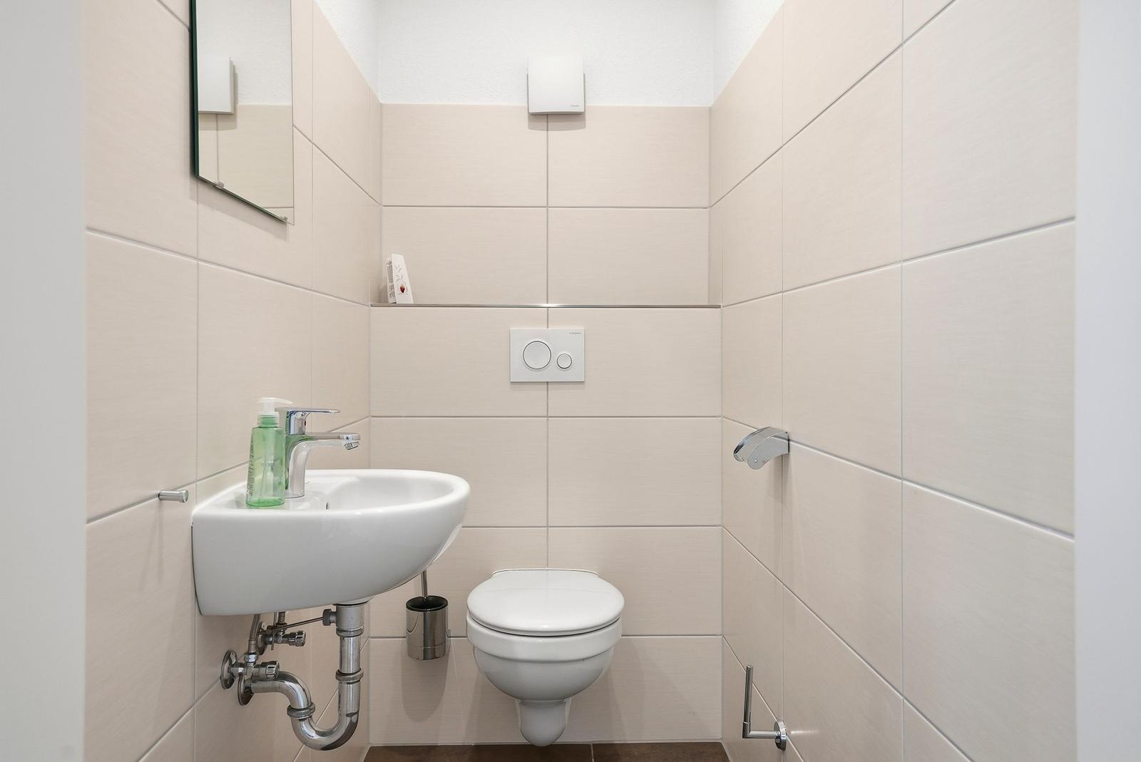 Badezimmer mit Toilette, Waschbecken und Spiegel an der Wand.