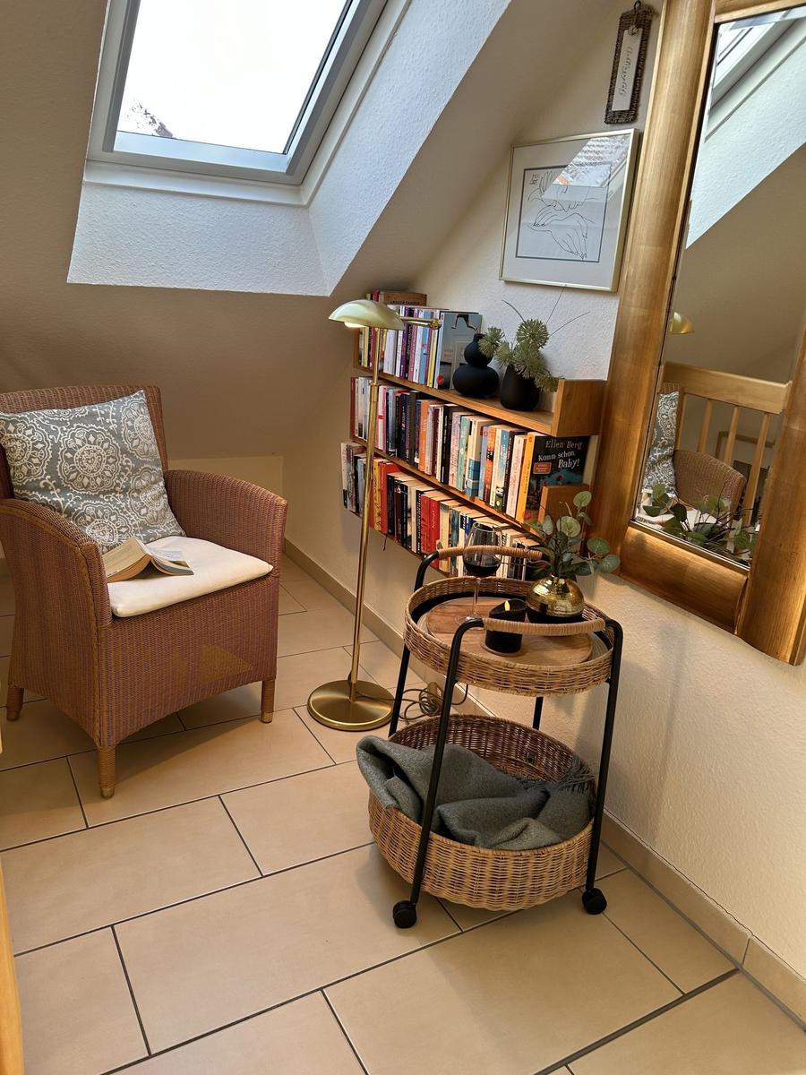 Wohnbereich mit Sessel, Bücherregal und Schieferdachfenster.