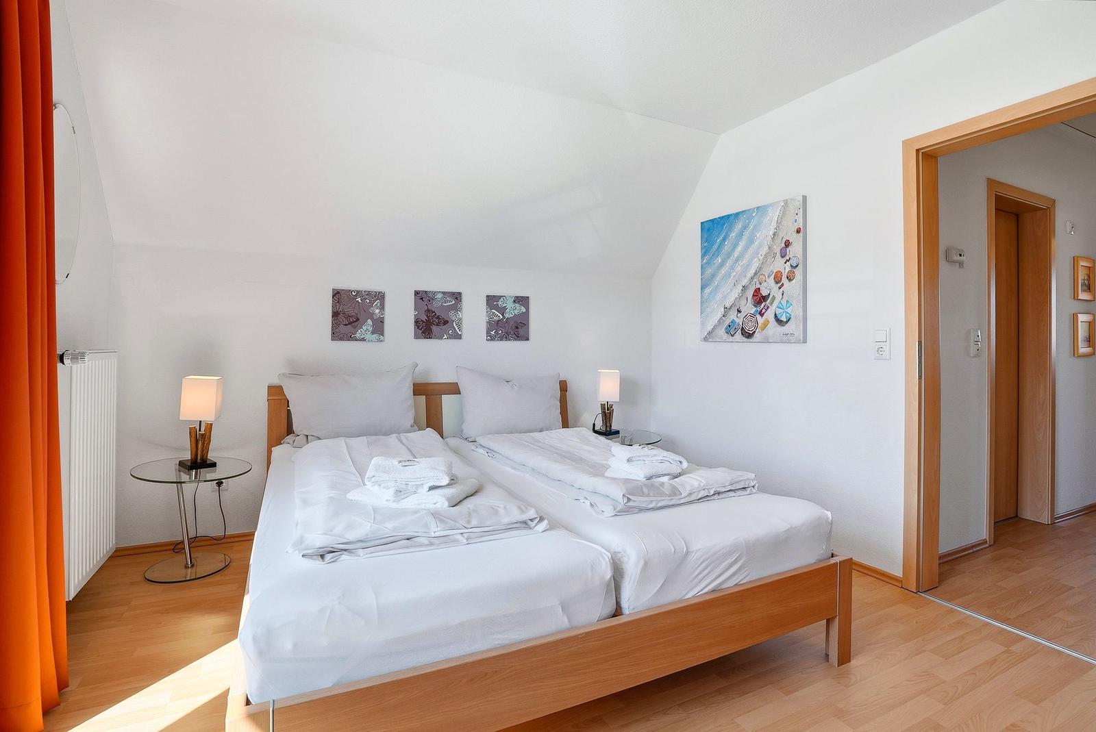 Schlafzimmer mit Doppelbett, zwei Nachttischen und Wandbildern.