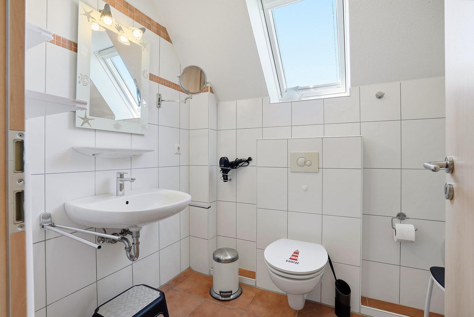 Badezimmer mit Waschbecken, Toilette und Dachfenster.