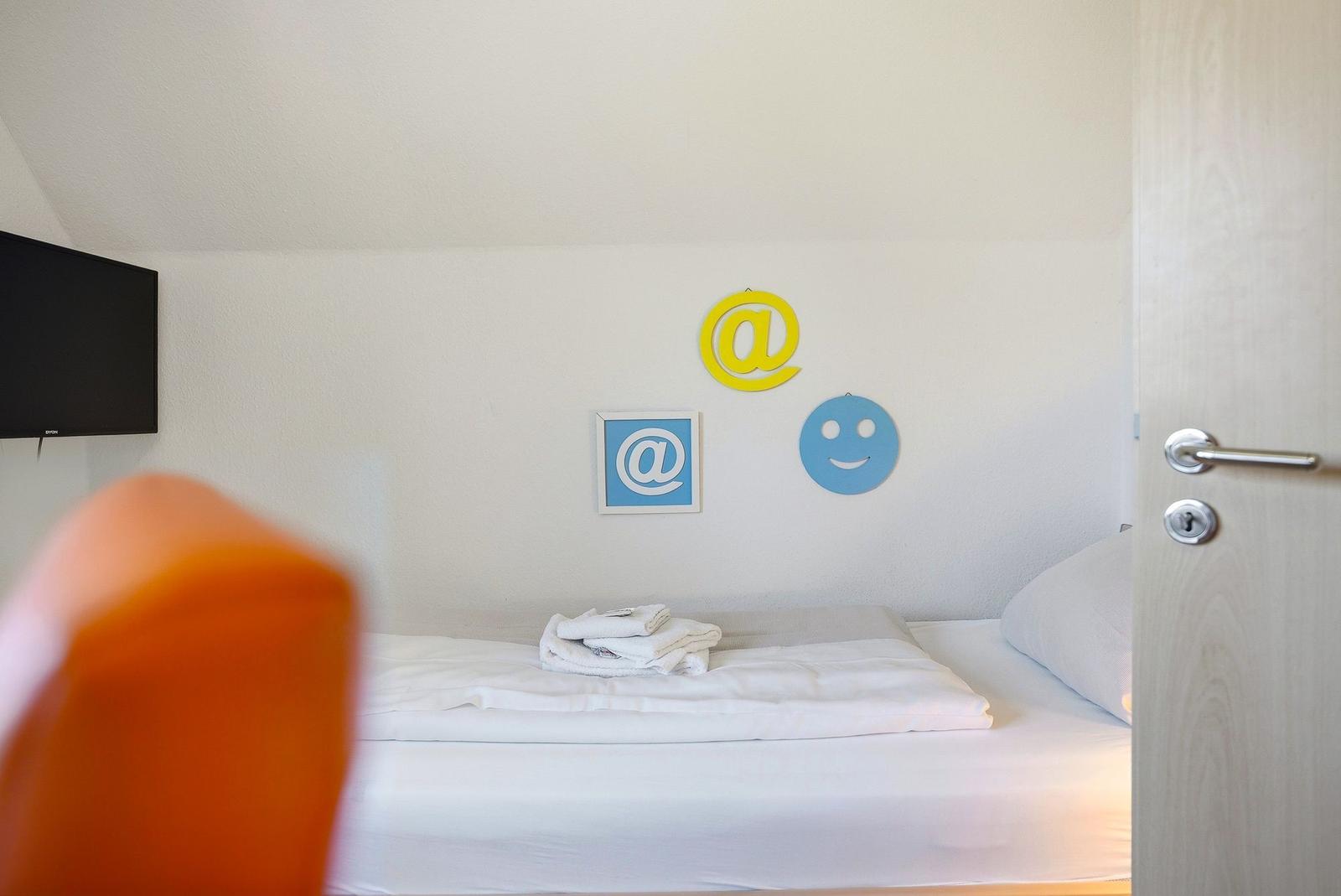 Schlafzimmer mit Bett, Wanddekoration und Fernseher.