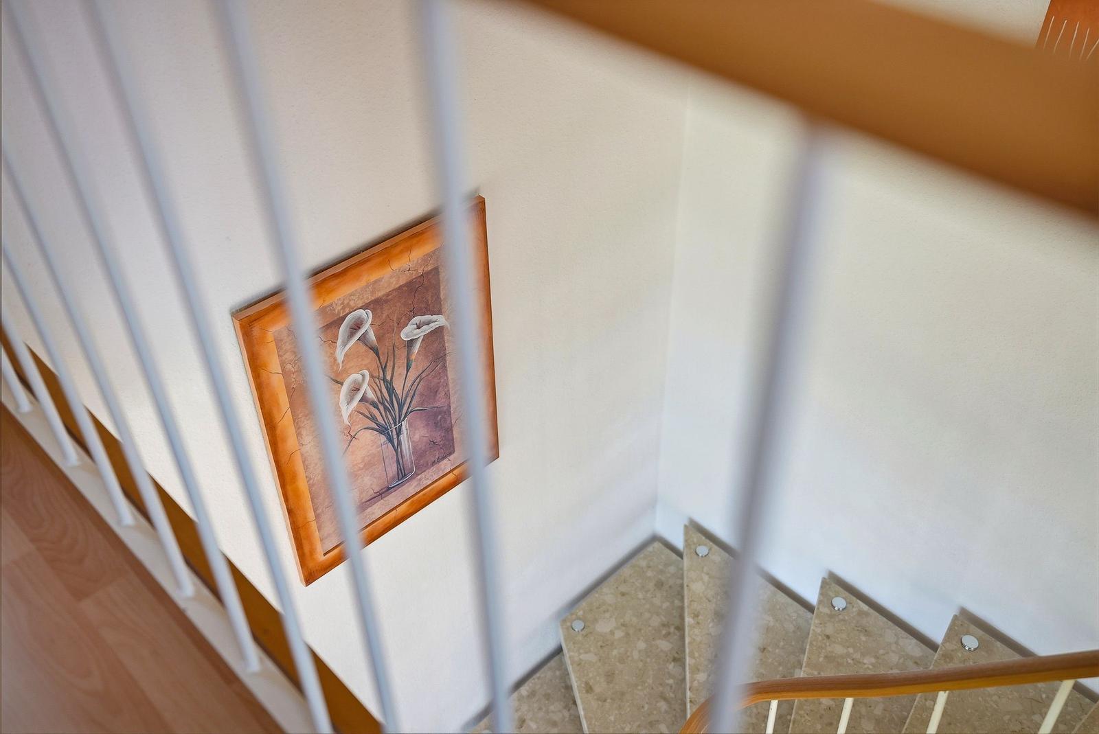 Treppenhaus mit Bild an der Wand und Holzgeländer