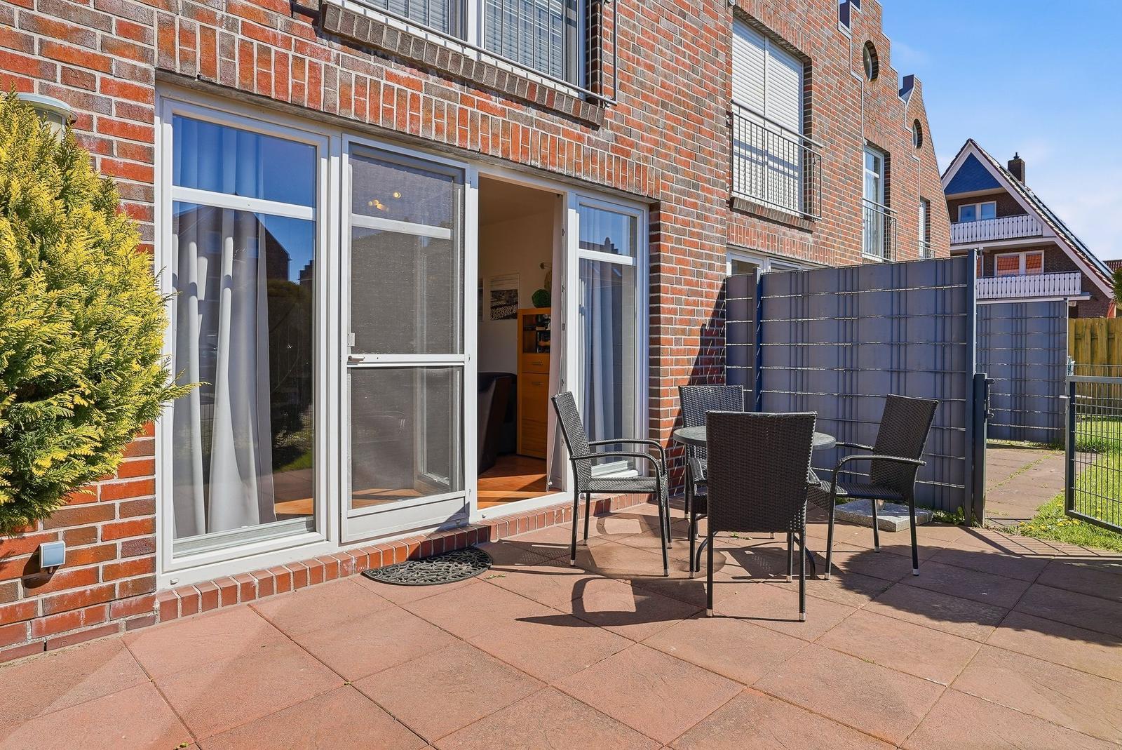 Terrasse mit Sitzgruppe vor einem Haus mit rotem Backstein und Glasfront.