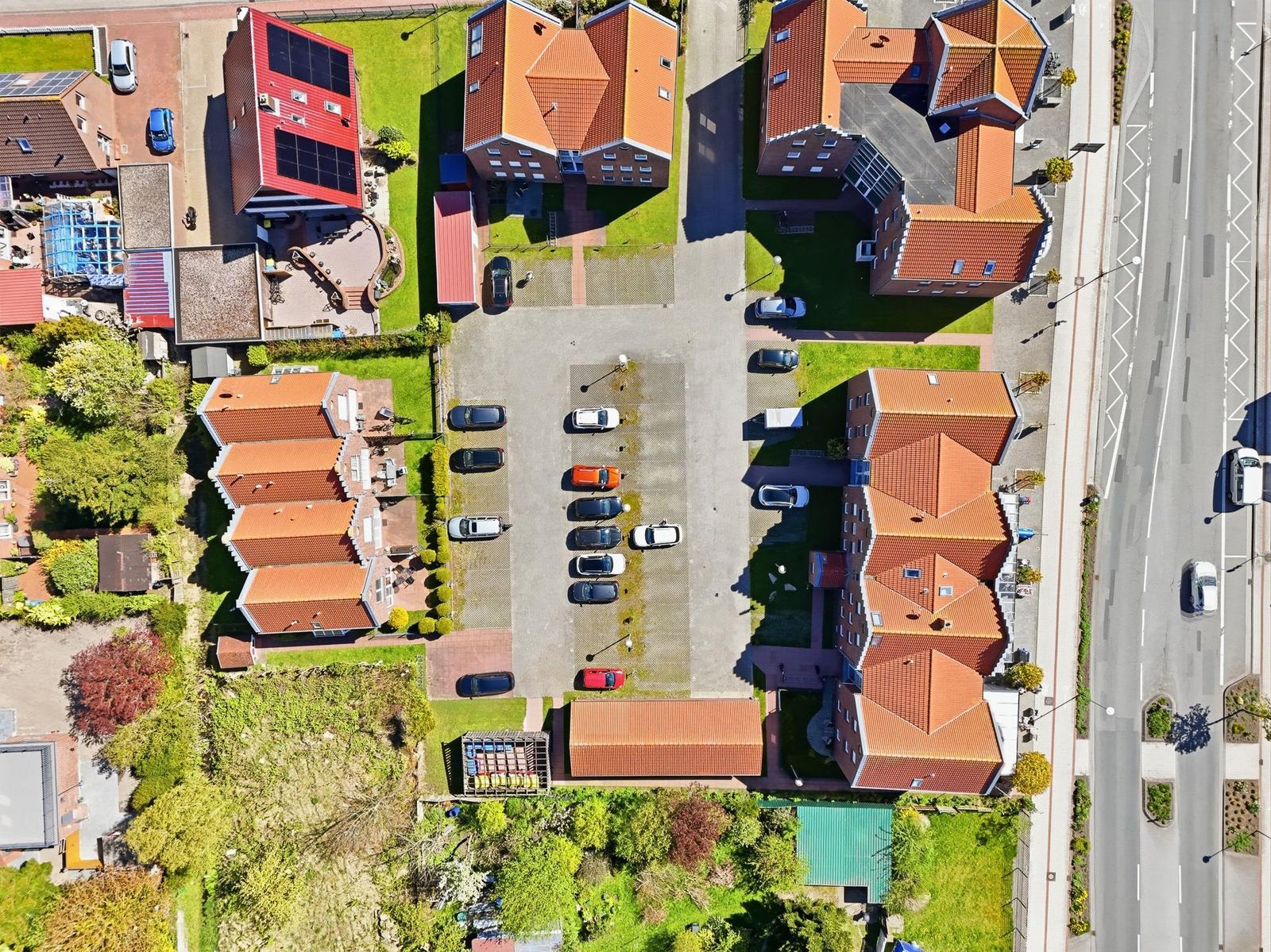 Luftbild von mehreren Häusern mit roten Dächern und Parkplätzen.