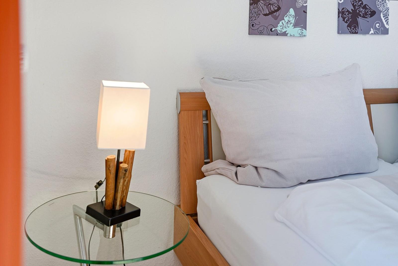 Bettkopfteil mit Kissen, Nachttisch mit Lampe und Wandbildern