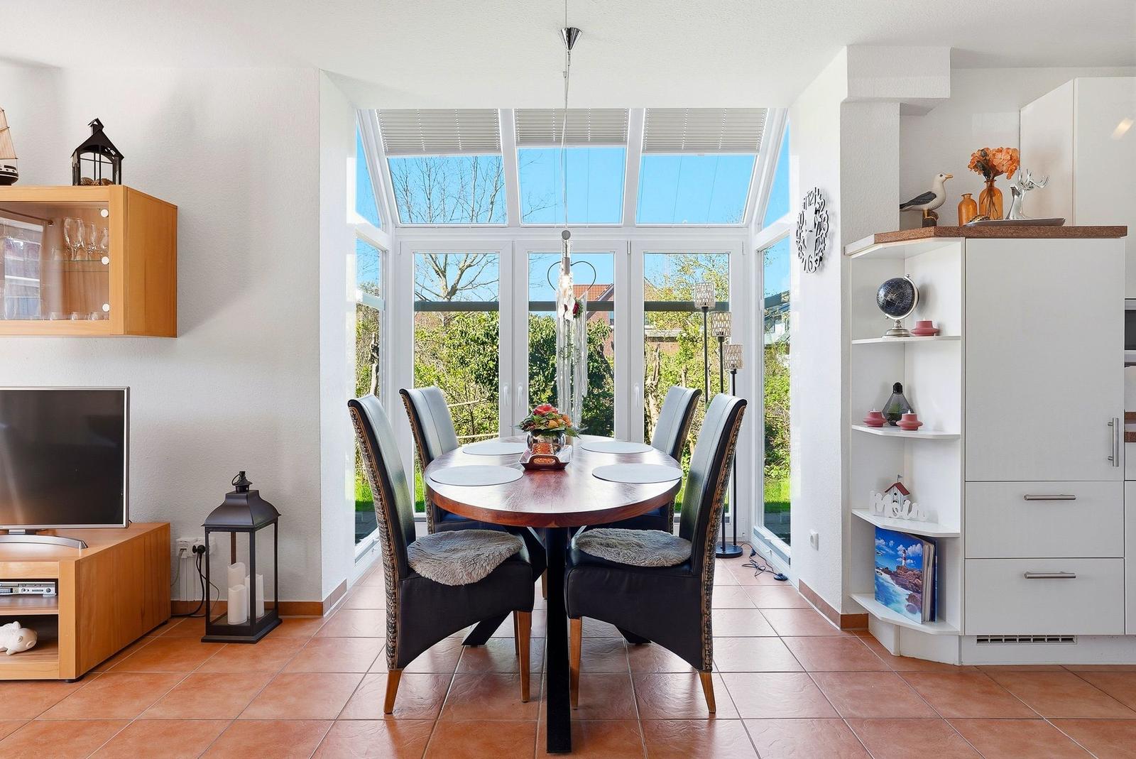 Esszimmer mit runden Tisch, Stühlen und großem Fenster zur Gartenansicht.