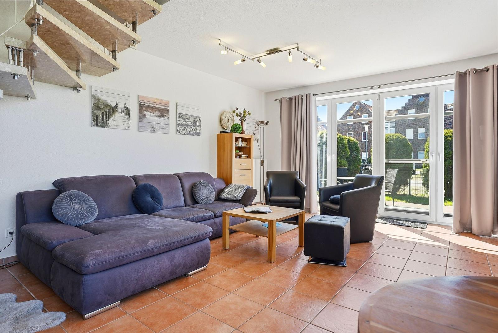 Wohnzimmer mit Sofa, Sesseln und Terrassentür