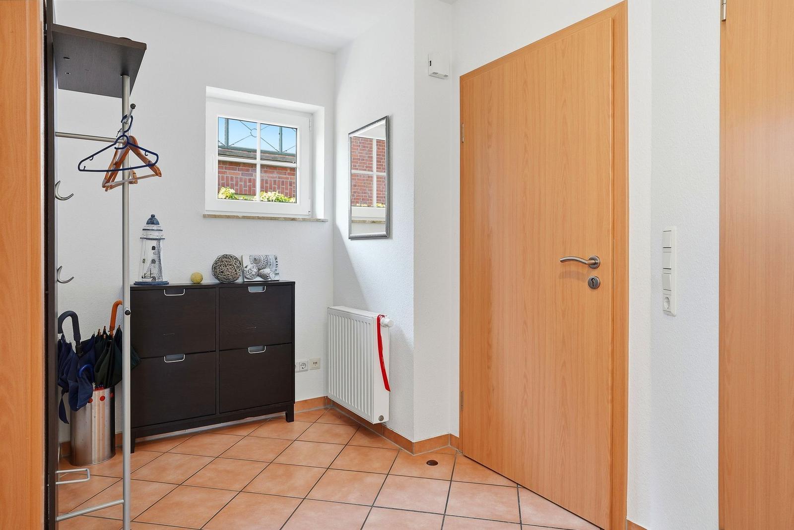 Eingangsbereich mit Kleiderständer, Schrank, Fenster und Tür.