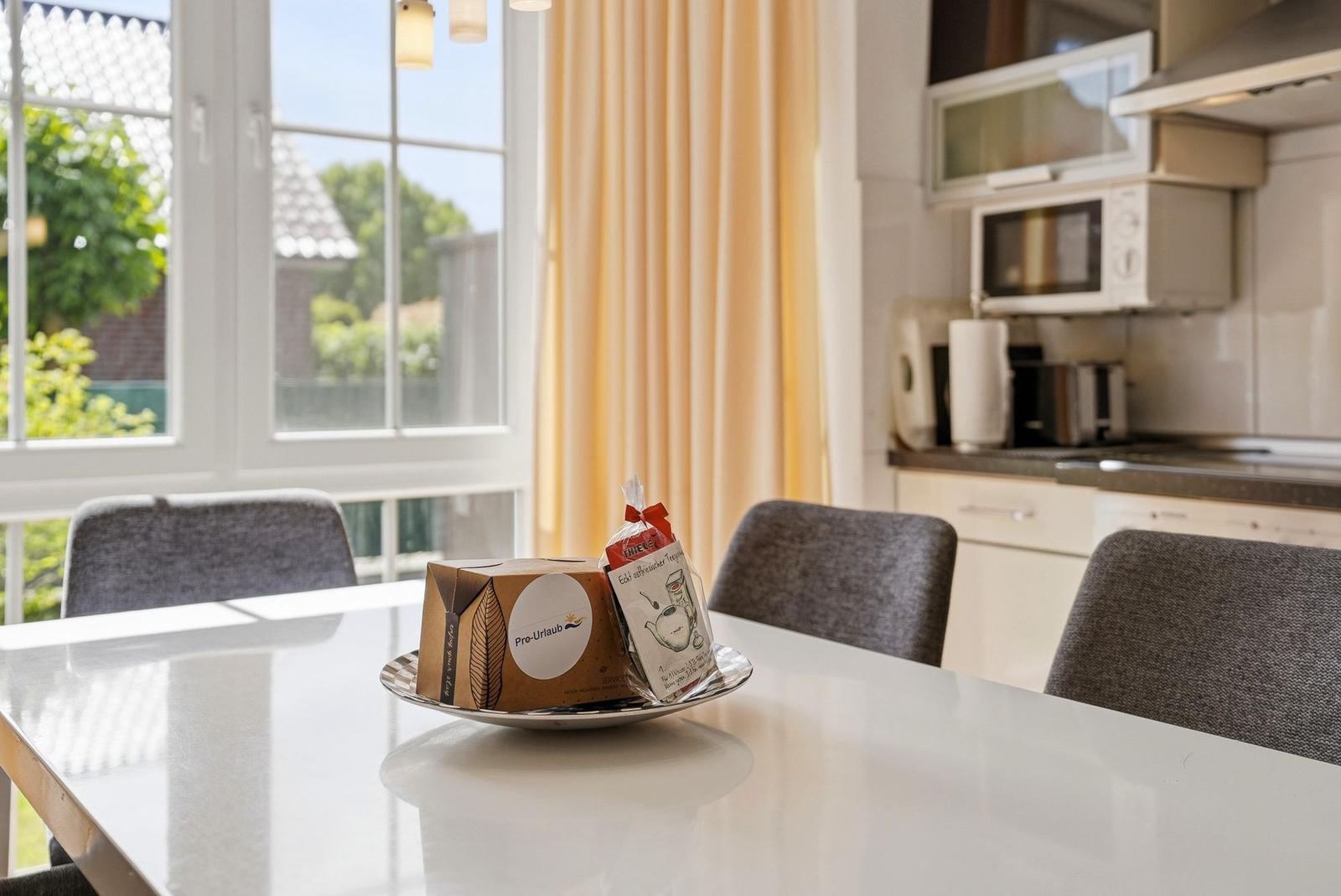 Tisch mit Tee und Keksen vor Fenster und Küche