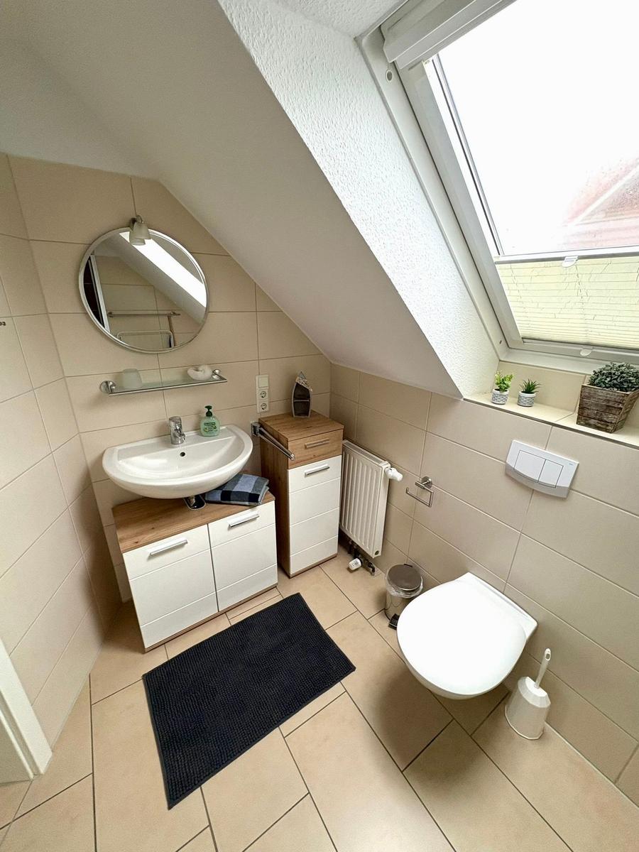 Badezimmer mit Waschbecken, Toilette und Dachfenster. Holz- und weiße Elemente.